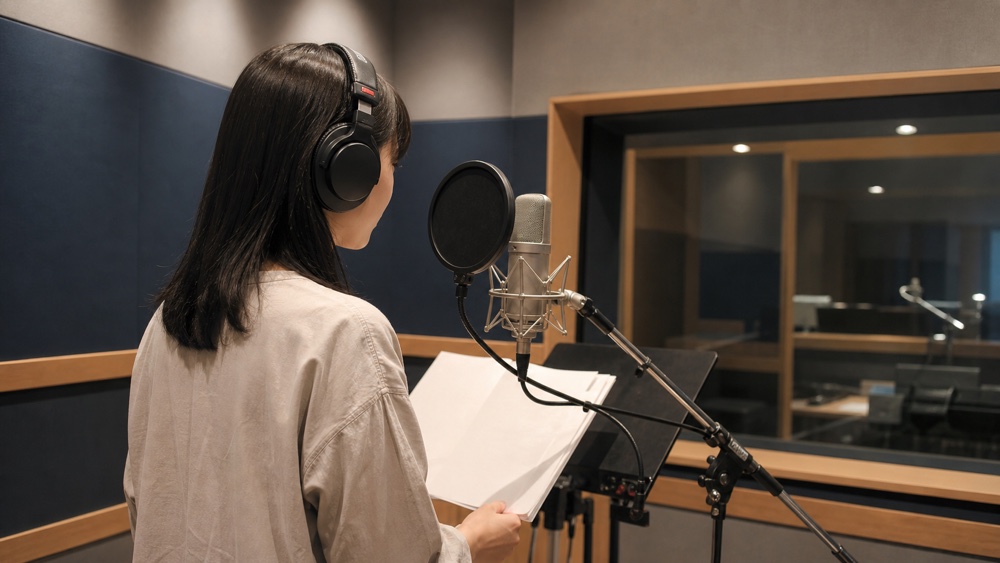 レコーディングブースで収録する声優志望者