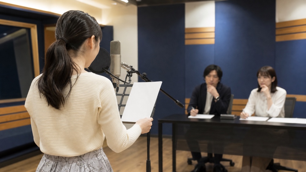 録音スタジオの入所オーディションで実技審査を受ける声優志望者