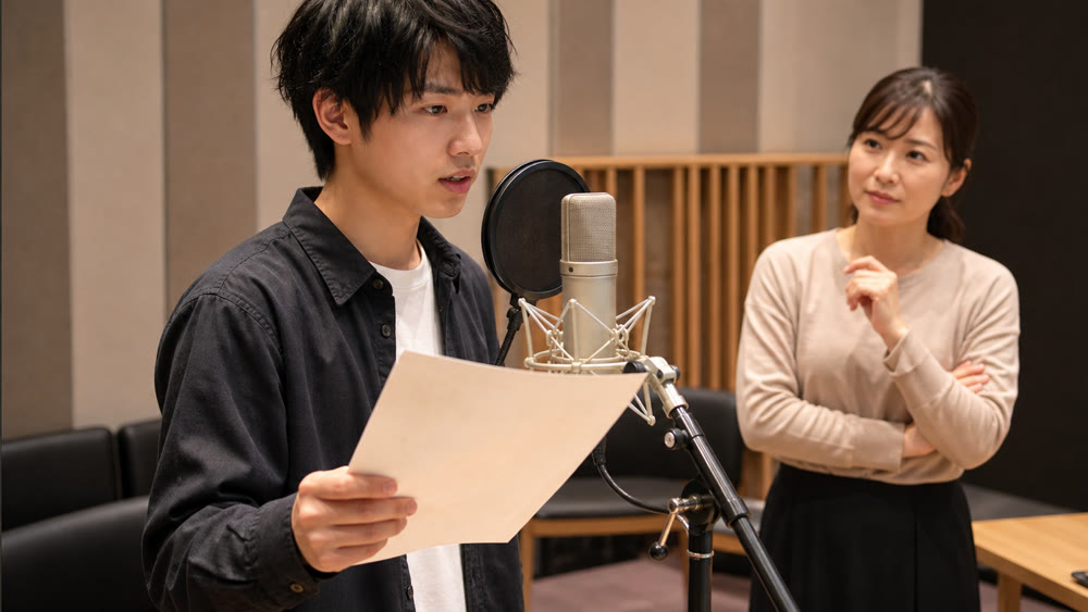 声優を目指してマイク練習に取り組む学生と講師