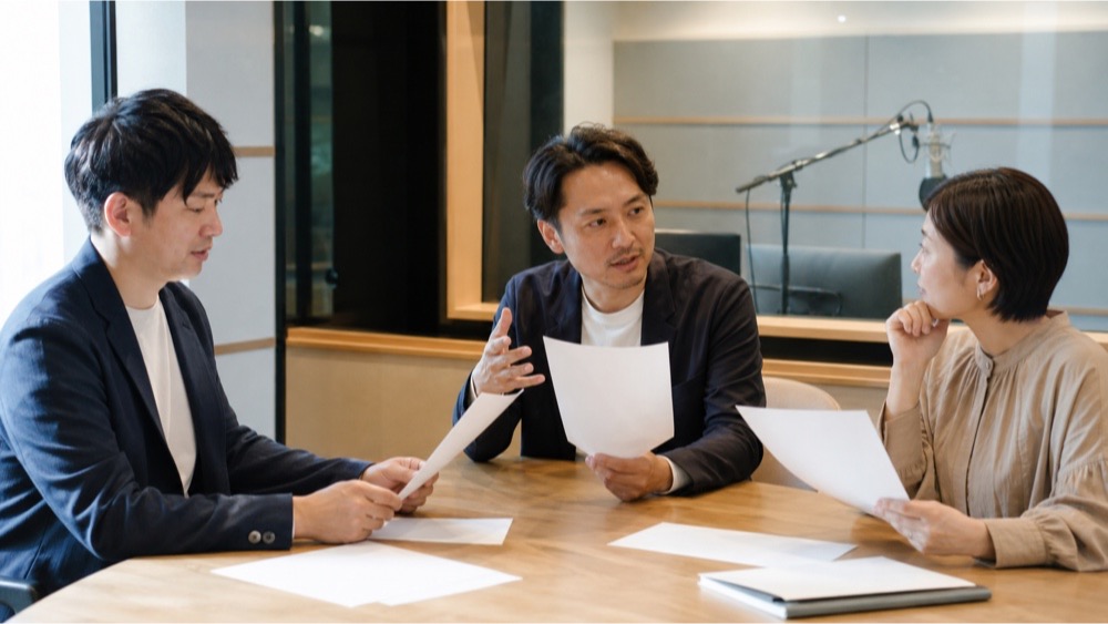 録音スタジオ併設校で進路資料を話し合う学校スタッフ