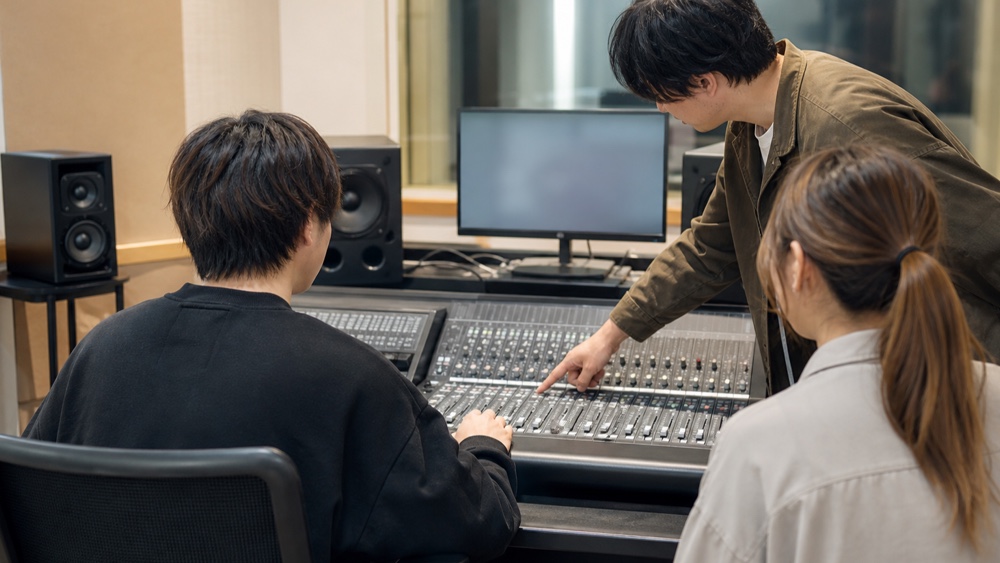 音響卓とPCを使って声の加工や収録を学ぶ学生