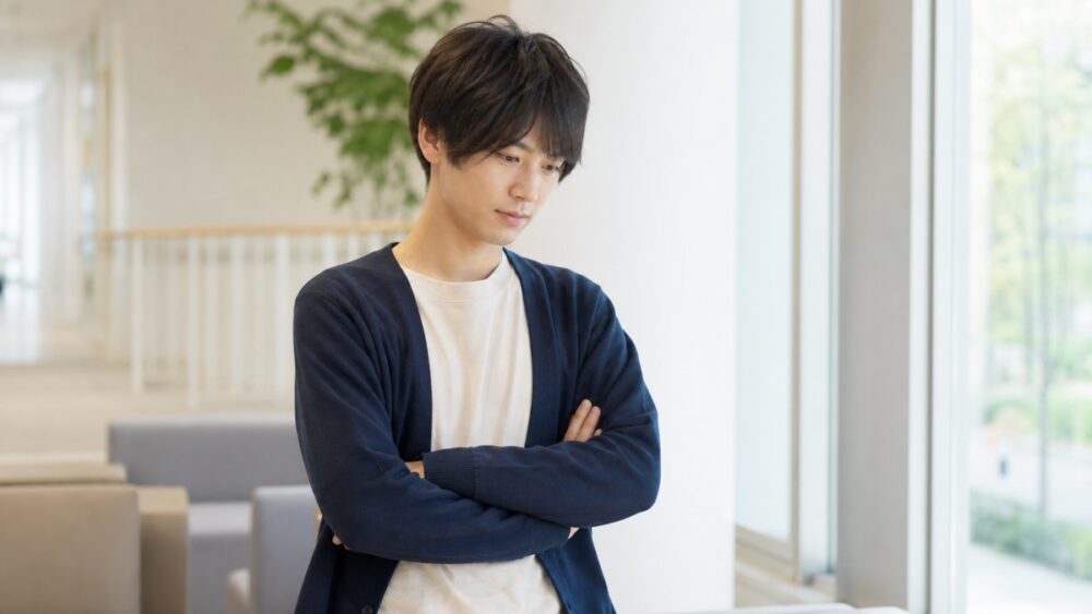 明るい室内で腕組みをして養成所の選択肢を考える人