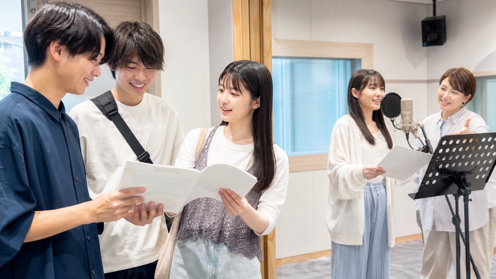 声優専門学校のオープンキャンパスでパンフレットを見ながら校内見学と体験レッスンを楽しむ学生
