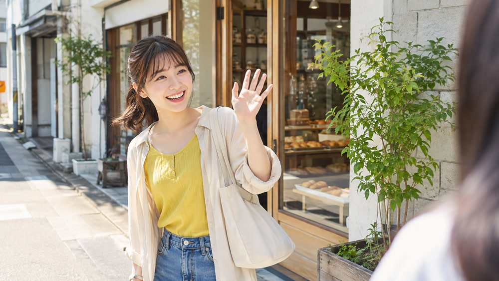 朝の街角で明るく挨拶する女性の日常シーン