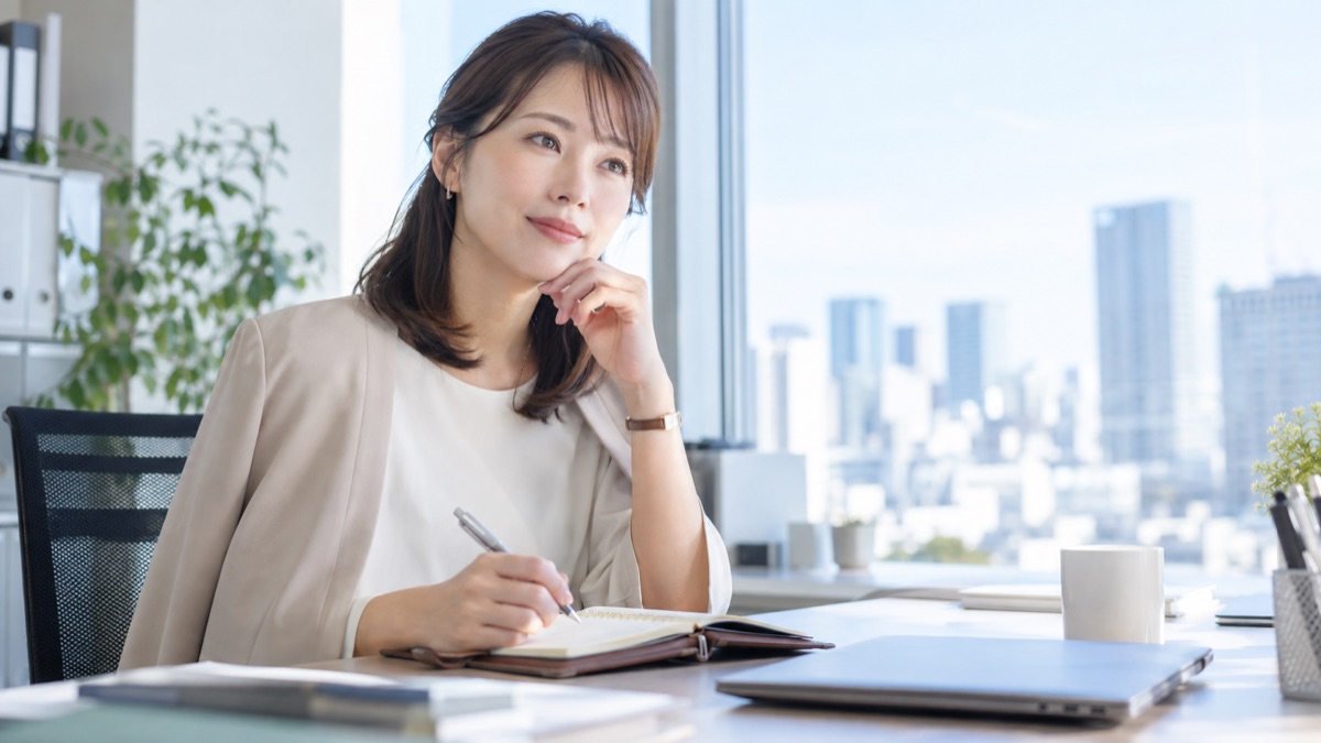 手帳に書きながら落ち着いて考える女性社員