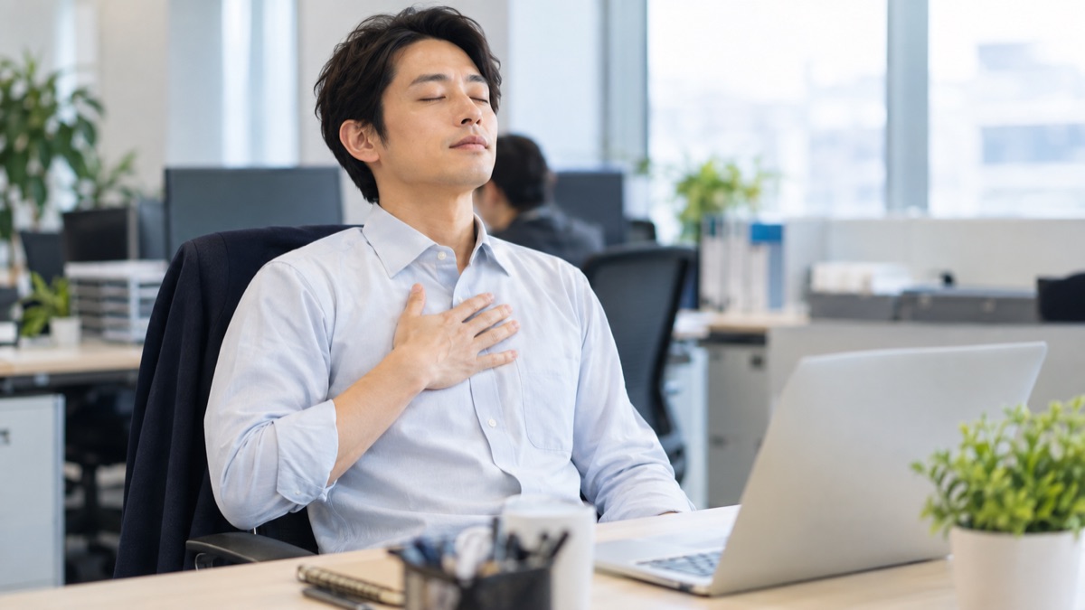 胸に手を当ててゆっくり息を吐く男性社員