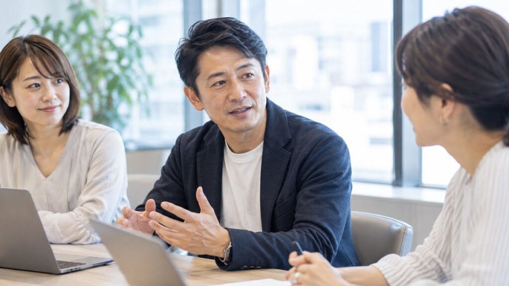 職場の打ち合わせで同僚と穏やかに向き合って話す男性