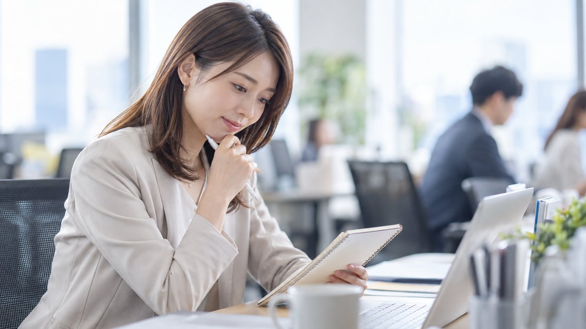 会議の前に手元のメモを見ながら考える会社員の女性