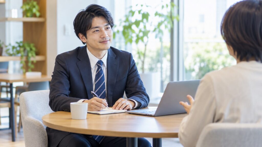 明るい商談スペースで、営業担当の男性がお客様の話にうなずきながら聞いている
