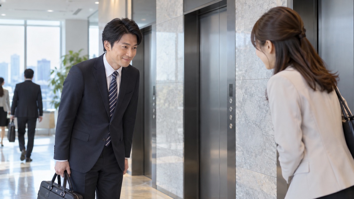 朝のオフィスのエレベーターホールで、同僚に会釈してあいさつする男性会社員