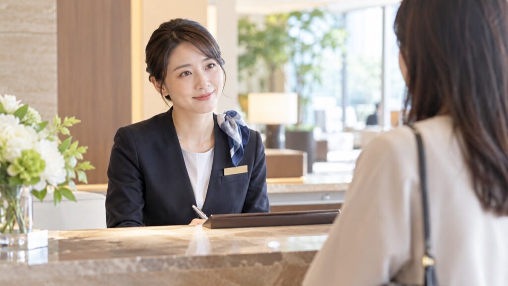 ホテルのフロントで落ち着いてお客様の話を聞く女性スタッフ