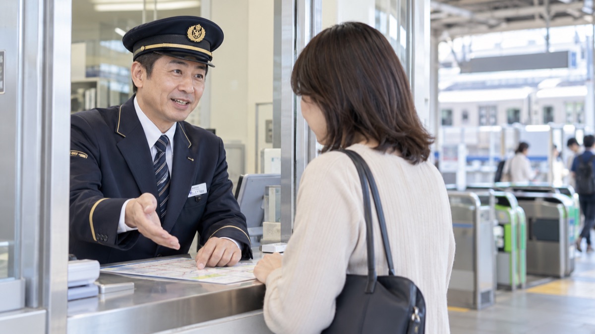 駅の改札横の窓口で乗客に案内する駅員