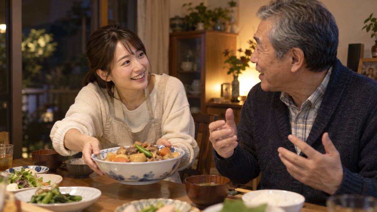 夜、実家の食卓で、30代の娘が、身を乗り出して熱心に話し込む60代の父親に、笑顔で大皿の煮物をすすめている