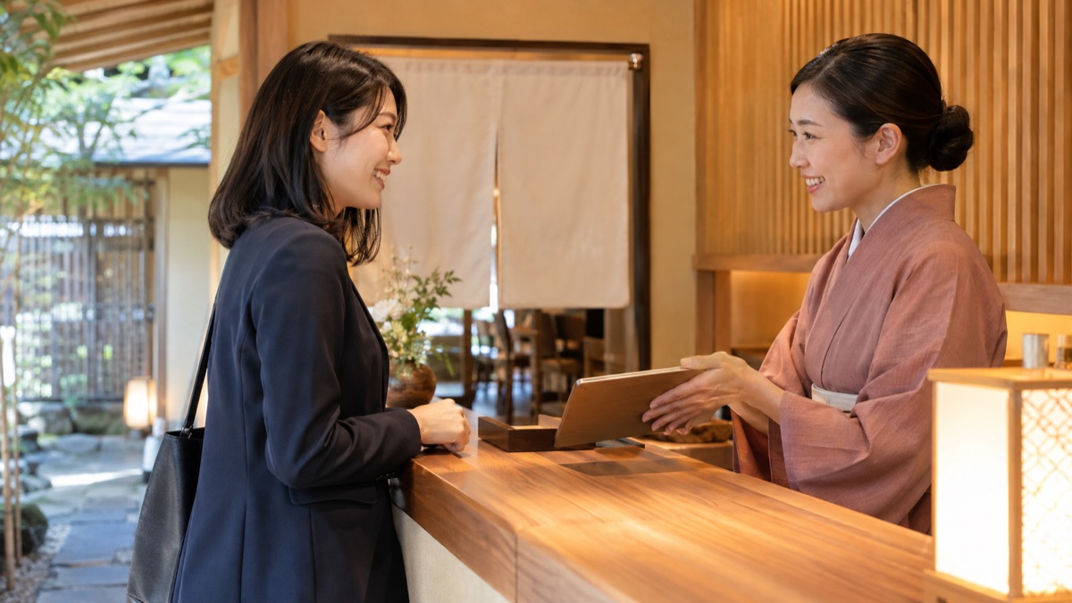和食店の入口の受付で、幹事が送別会の予約と席の流れを店員と確認している