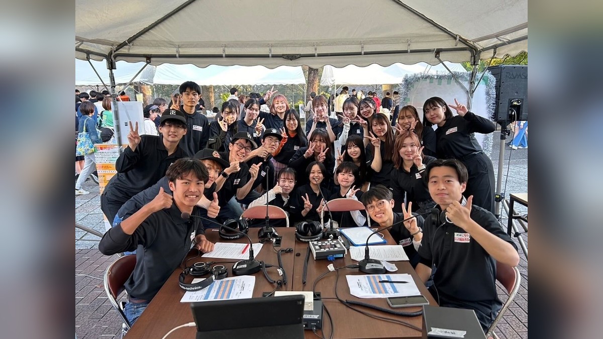 ラジオ班の学生たちが屋外のブースでそろって記念撮影している様子