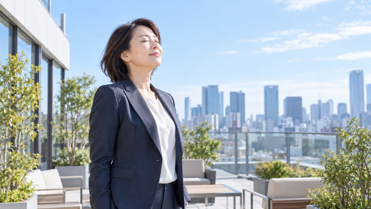 屋上テラスで女性管理職が目を閉じてゆっくり息を吐く