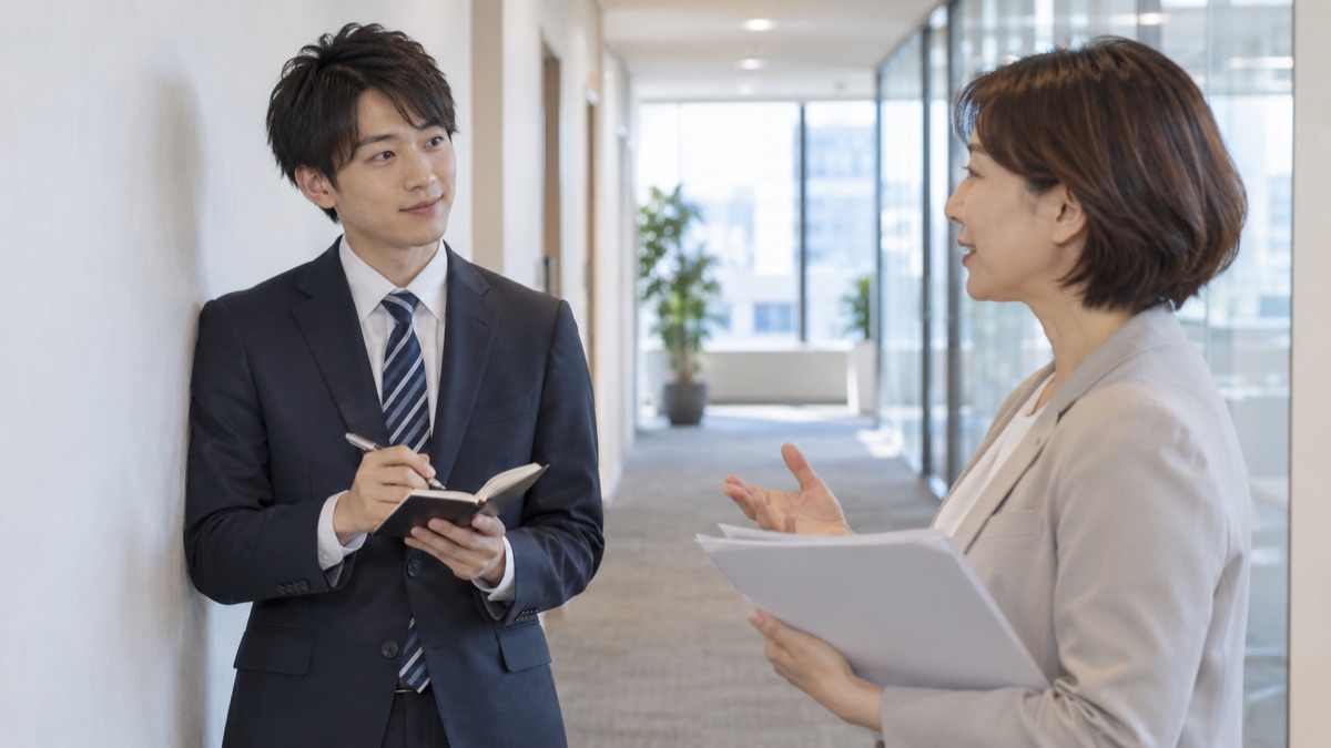 打ち合わせで相手を見てうなずきながら、ノートに短くメモを取る女性社員