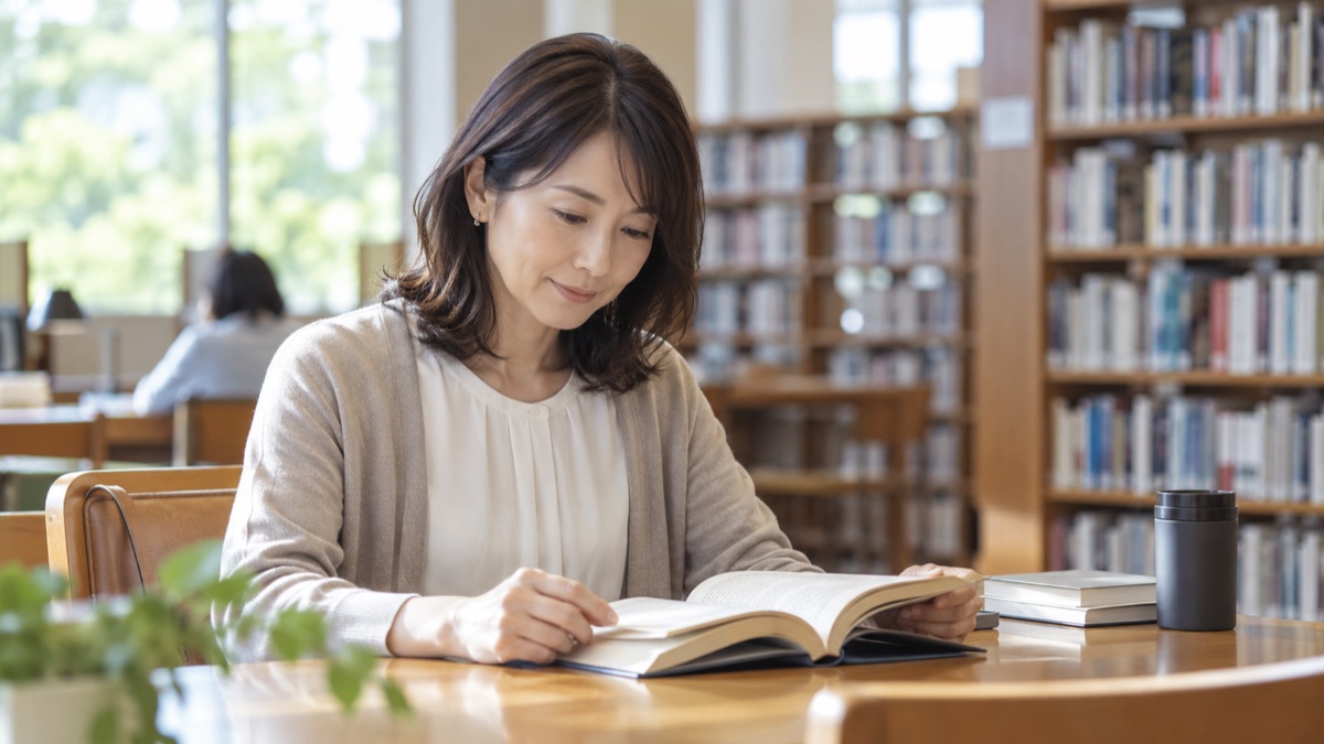 図書館の閲覧席で、本を開いて落ち着いて読む女性
