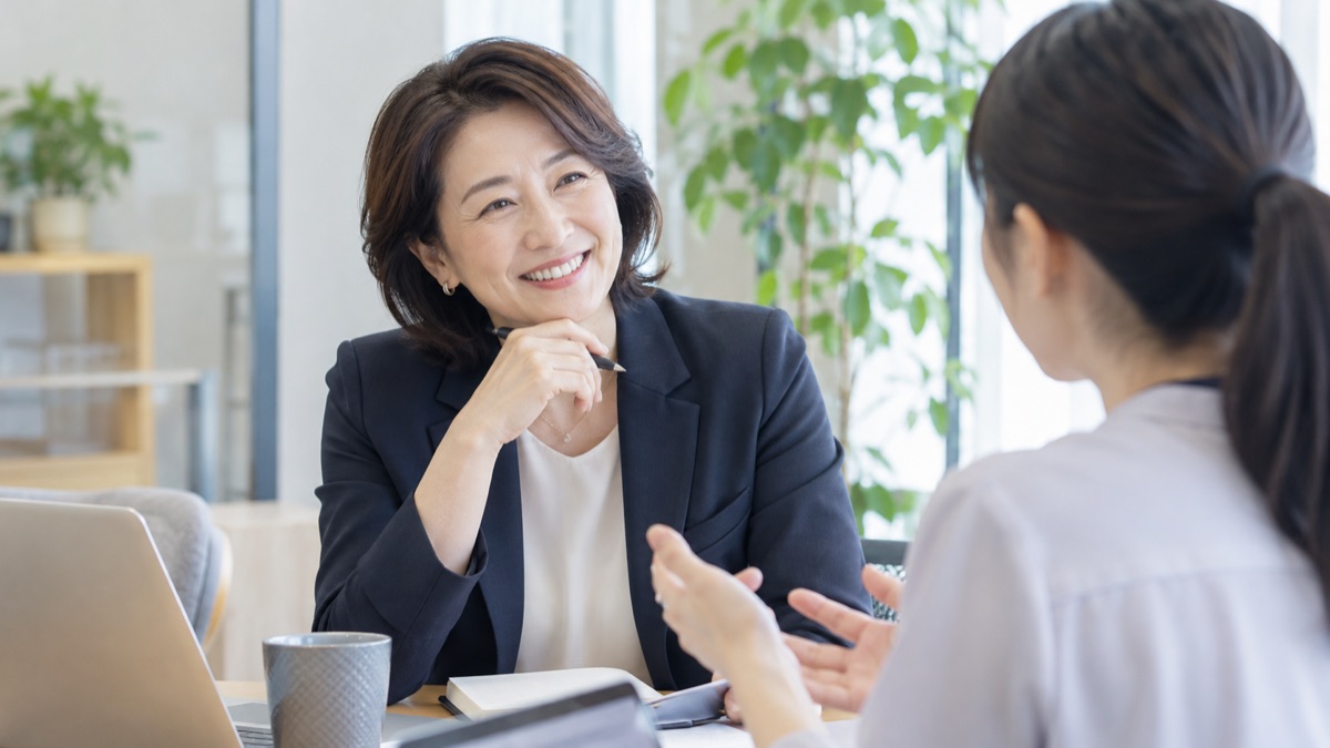 打ち合わせスペースで部下の話に笑顔でうなずく女性管理職