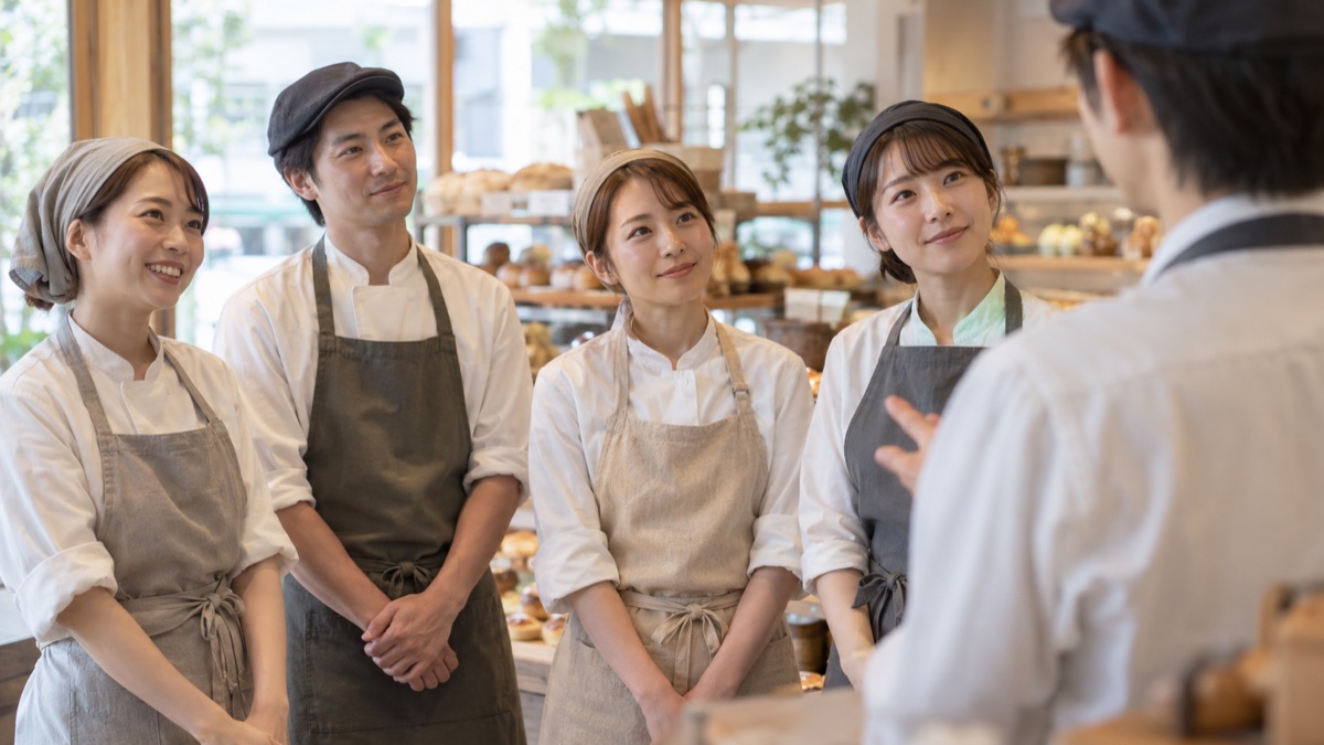 開店前のパン屋で店長の話をリラックスして聞くスタッフ