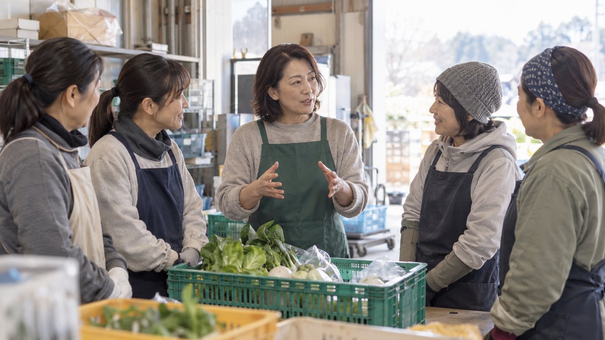 1月の午後、農産物の直売所の裏の作業場で、エプロン姿の40代の女性部長が、野菜の入った箱を前に4人のパート職員と立ったまま話している
