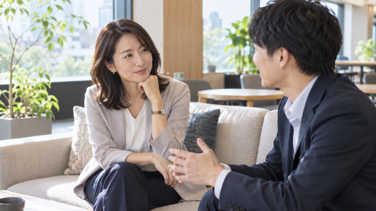 ラウンジのソファで後輩の話をうなずきながら聞く女性社員