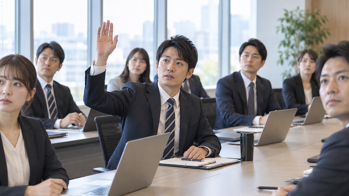 朝の会議室で、少し緊張しながら手を挙げて質問しようとする男性会社員