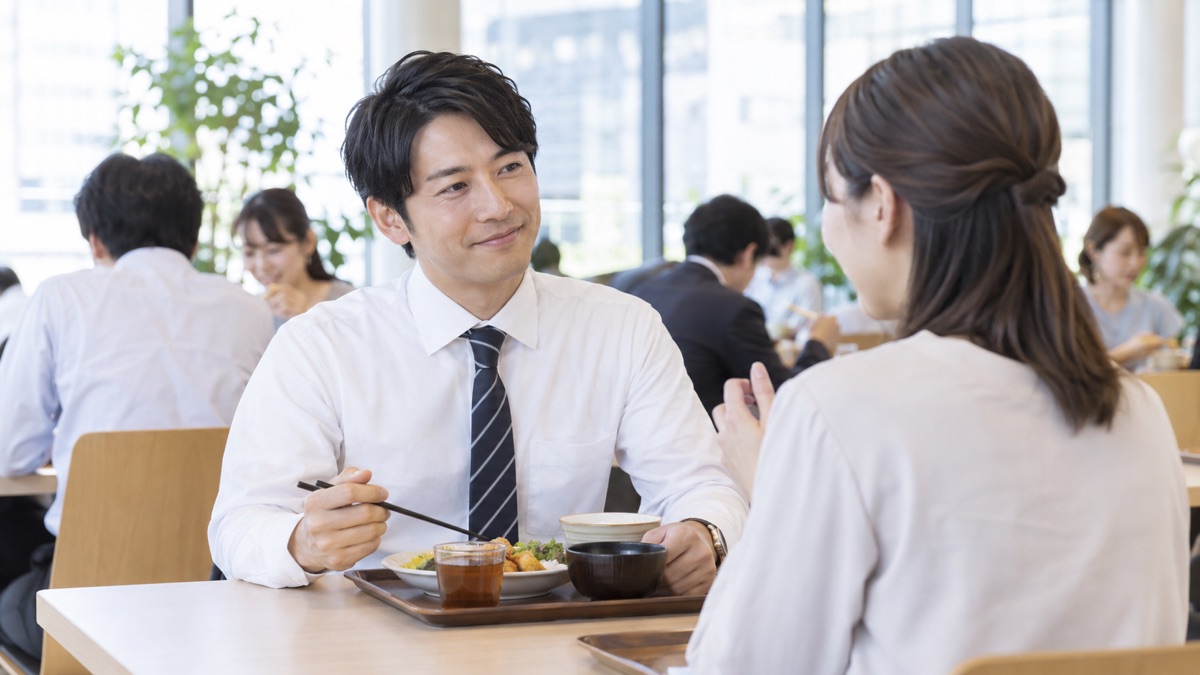 社員食堂で同僚の話にうなずきながら耳を傾ける男性