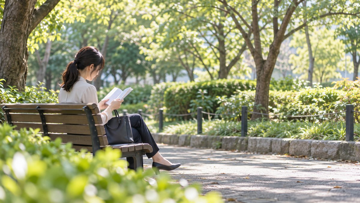 昼休み、会社近くの公園のベンチで、30代の女性会社員が薄い冊子を両手で開き、小さく声に出して読んでいる遠景。木漏れ日と植え込みの緑。高層ビルは写さない。冊子の文字は読めない。顔ははっきり写らない。文字は無い