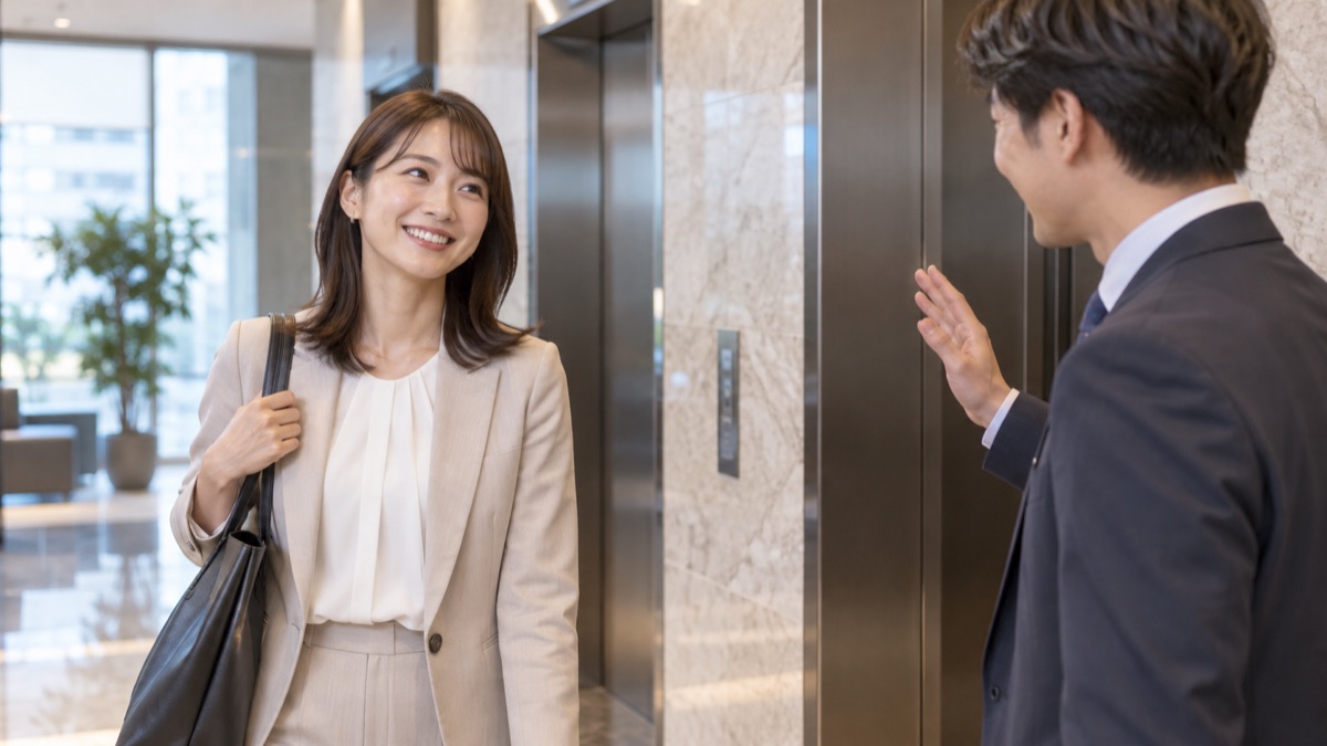 エレベーターホールで、取引先と笑顔で言葉を交わす女性営業