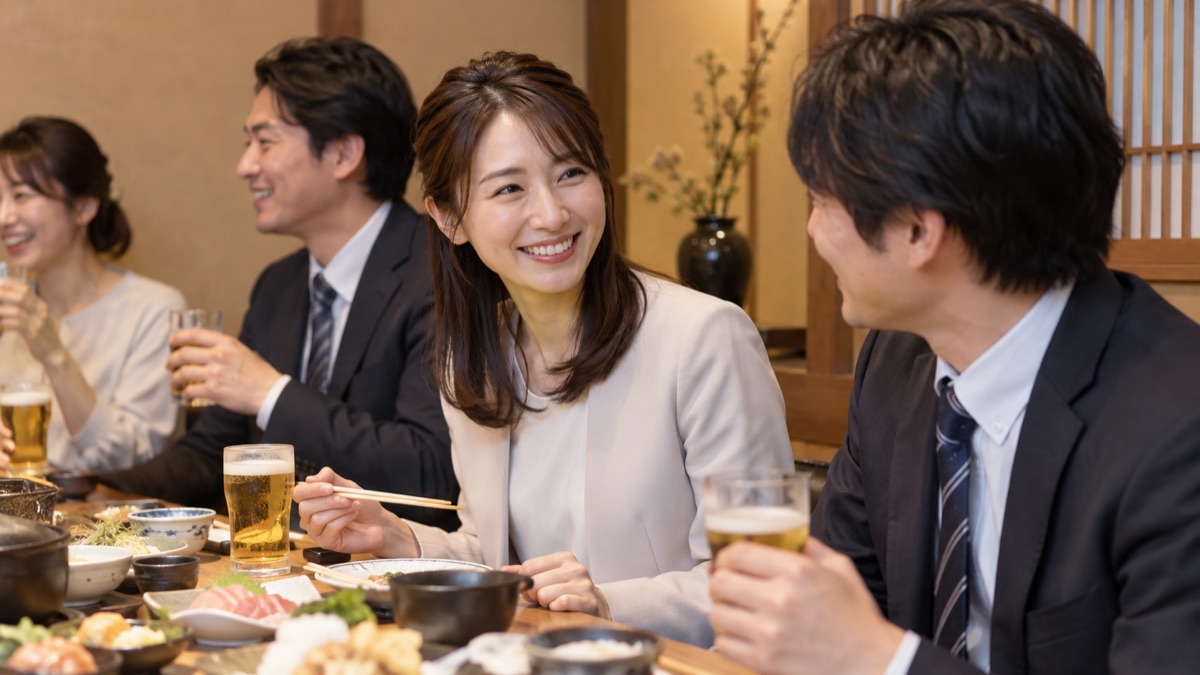 歓送迎会の席で、隣の同僚に笑顔で話しかける女性会社員