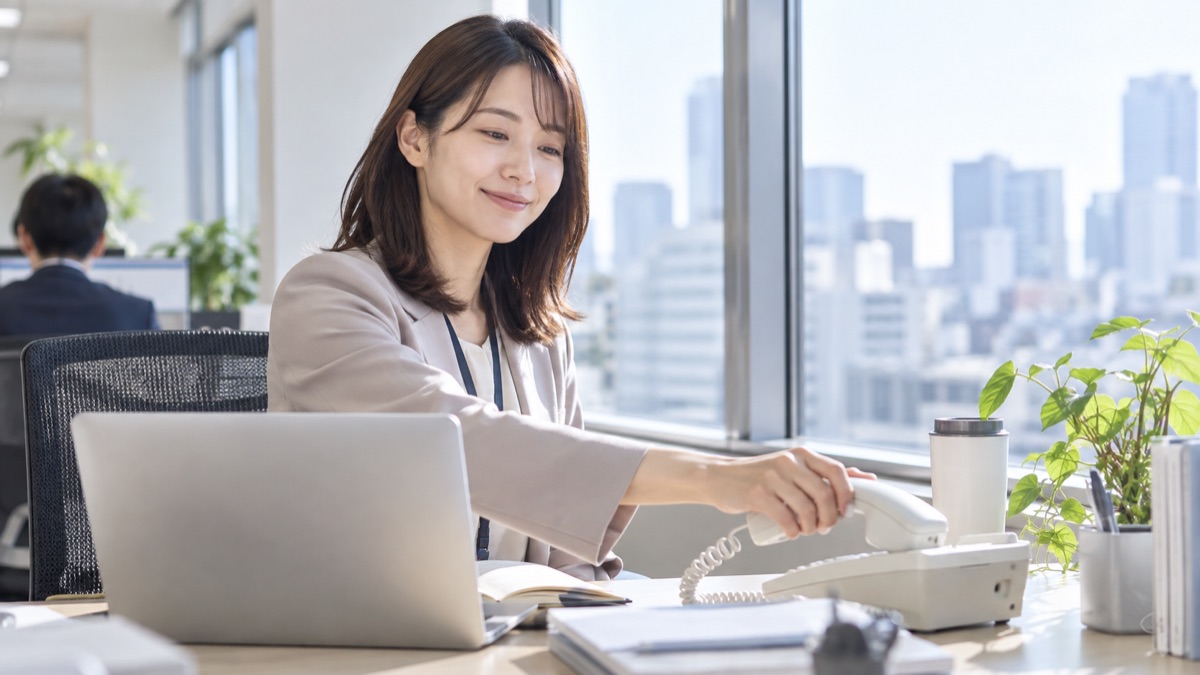 電話を終えて、ほっとした表情で受話器を置く女性会社員