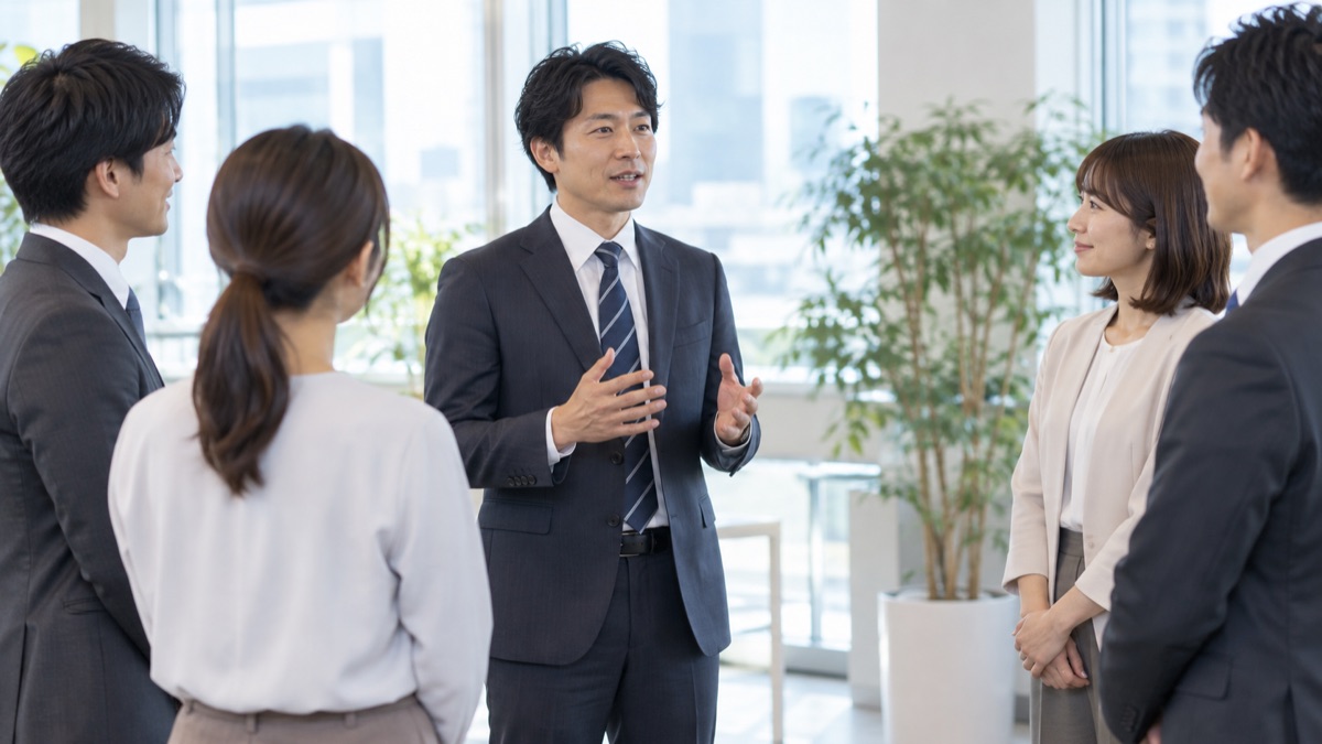 朝礼で、半円に並んだ同僚の前で短く話す男性会社員