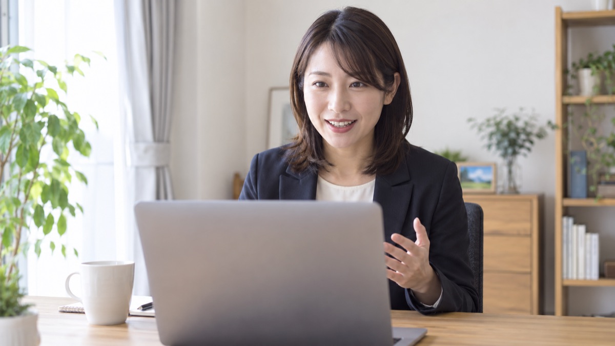 自宅のデスクで、ノートパソコンのカメラに目線を向けてWeb面接を受ける30代の女性